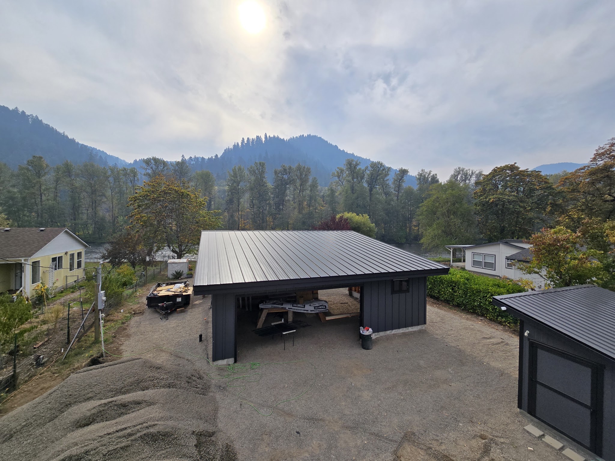 New carport and garage structure with standing seam metal roof and dark board and batten siding