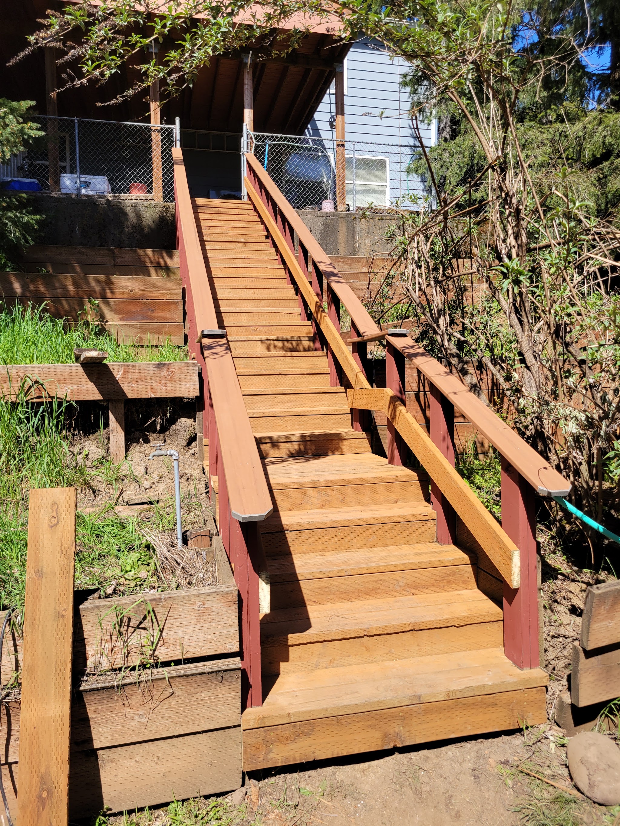 Finished hillside staircase with red stained rail posts and cedar treads